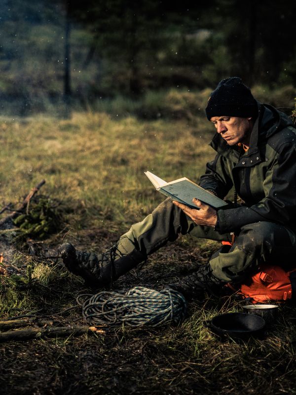 man reading a book in the woods
