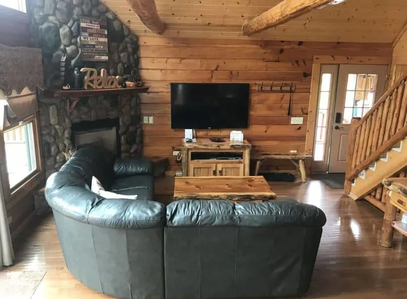 sofa in a living room with fireplace and TV at Hana Log Cabin near Devil's Lake in Baraboo, Wisconsin Dells