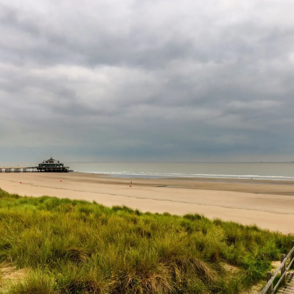 a view of the beach and pier under a cloudy sky