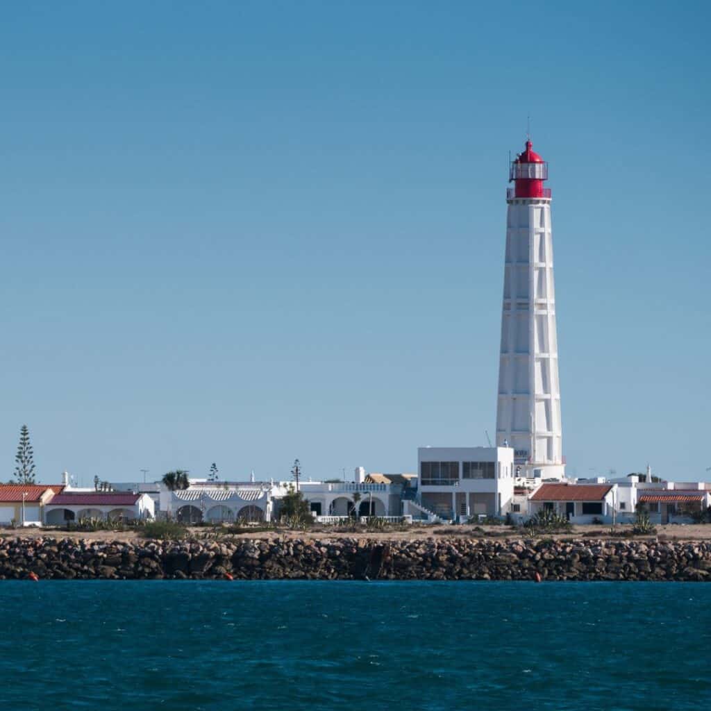 an island with buildings and a high light house with a red top