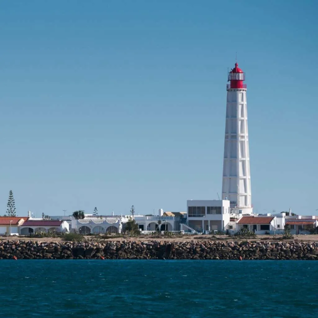 an island with buildings and a high light house with a red top