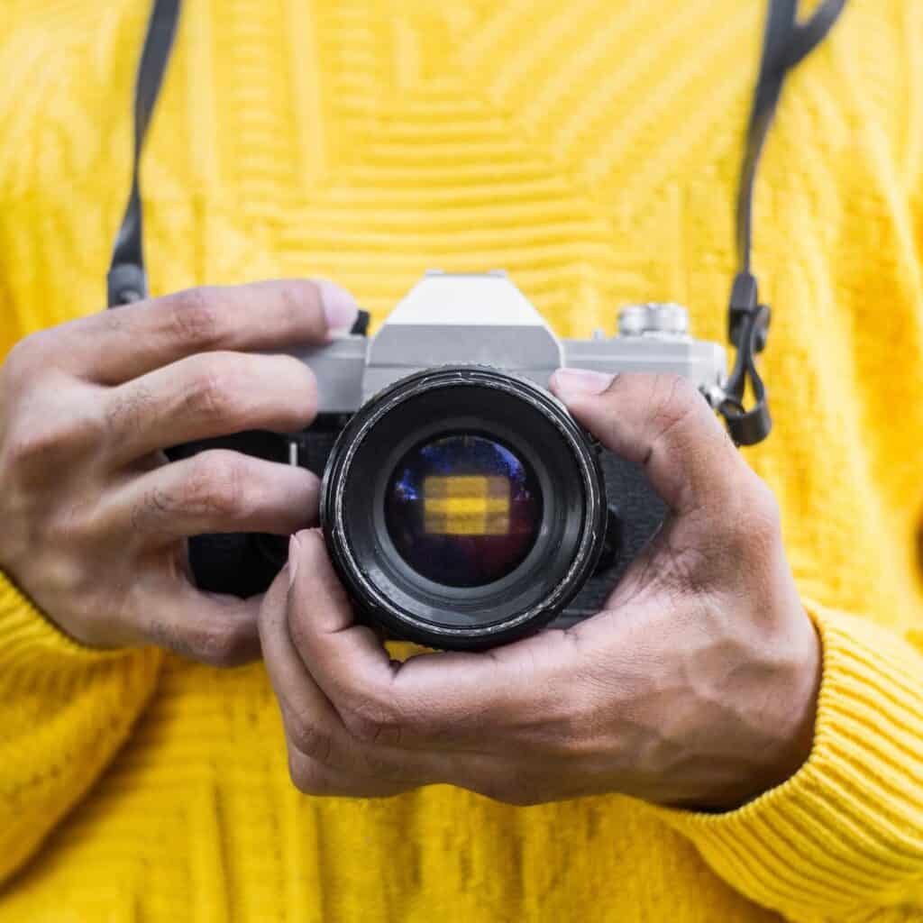 a person in a yellow sweater holding a camera