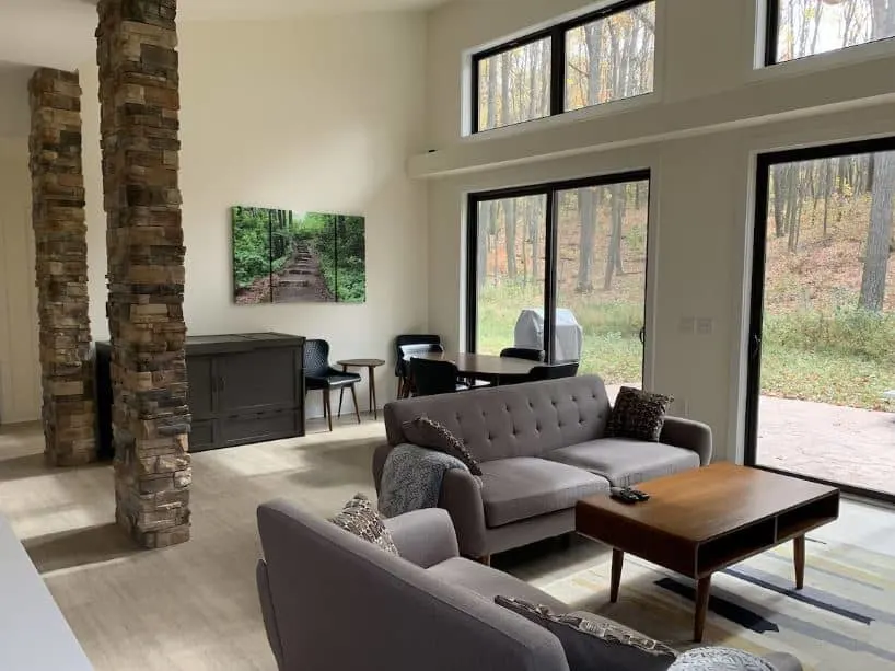 living room with 2 sofas and big windows overlooking the forest at the Beautiful home in a quiet wooded area in Baraboo, Wisconsin