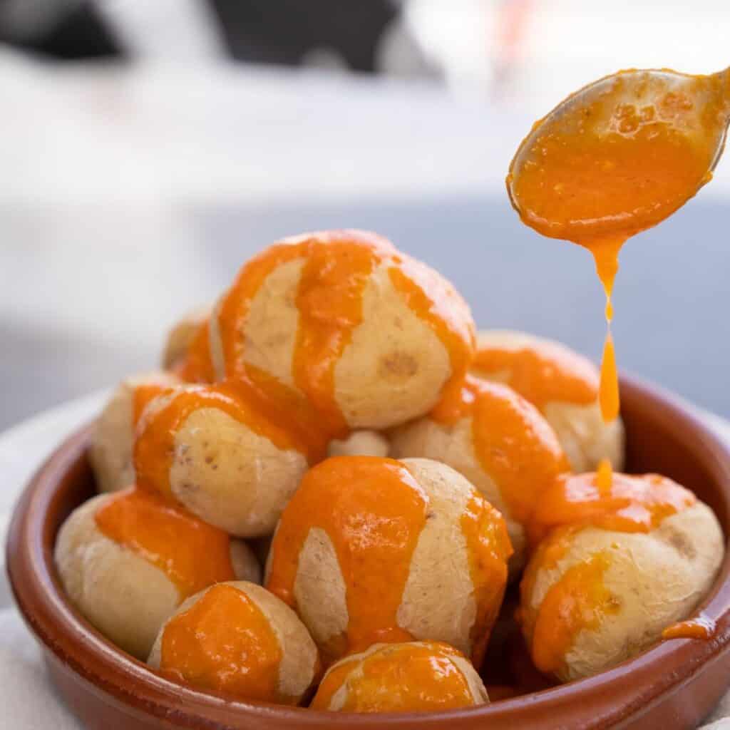a bowl filled with boiled potatoes covered in orange sauce