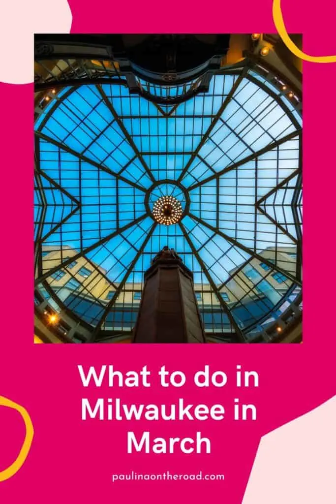 Pin with image looking up at a tall stone tower with a statue of a robed figure on top with a large geometric glass ceiling and lit chandelier above with the clear azure blue sky beyond, caption reads: What to do in Milwaukee in March from paulinontheroad.com