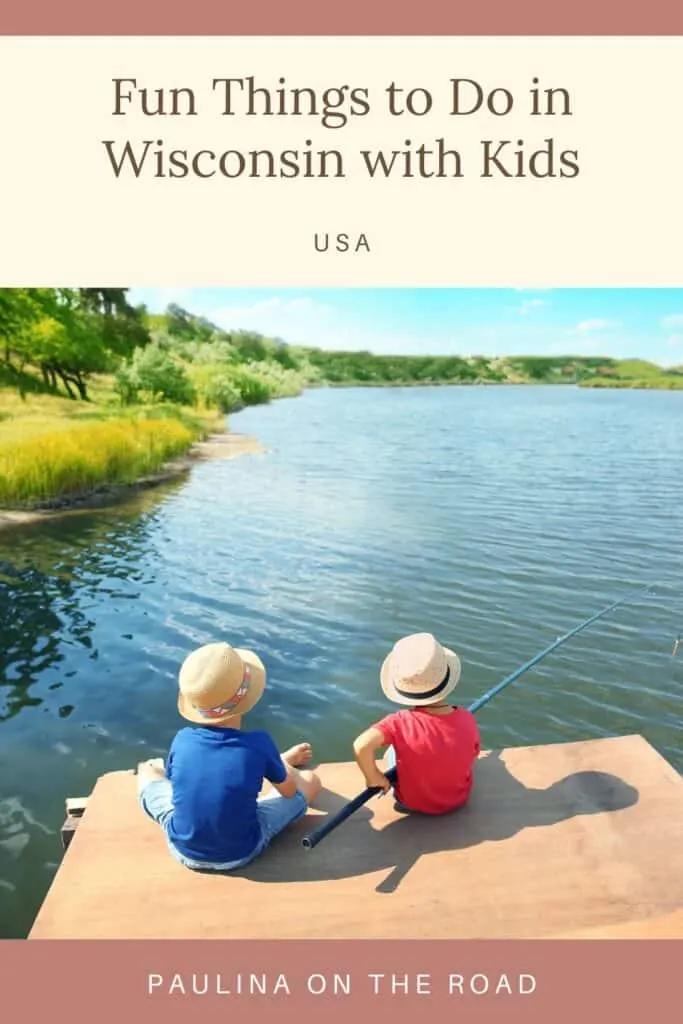 Pin with image of two children in red and blue t-shirts and white trilby hats sitting on a pier and holding a fishing rod over a large lake surrounded by lush green grass and trees under a bright blue sky, caption reads: Fun Things to Do in Wisconsin with Kids, USA from Paulina on the Road