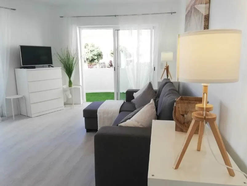 living room area with TV and sofa and a balcony at Charming apartment near the beach in Albufeira, Portugal