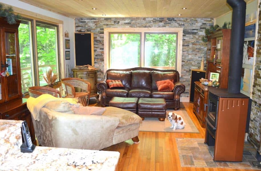 living room with sofa, fire place and windows overlooking the forest at Beautiful Cabin in the Woods Near Bayfield, Apostle Islands, Wisconsin
