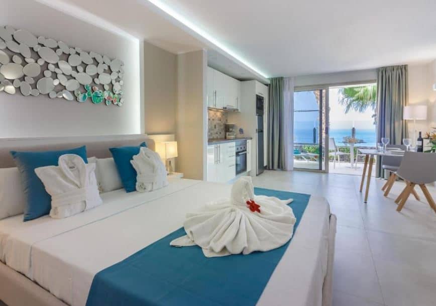 room with a bed, small kitchen, dining area and a balcony overlooking the sea at Klayman Diamond Aparthotel in Acantilado de los Gigantes, Tenerife