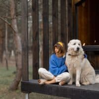 woman with her dog sitting on the porch of one of the best Pet-Friendly Cabins In Northern Wisconsin