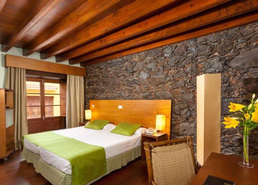 bedroom with stone walls, a desk with yellow flowers on it at the Hotel LIVVO La Quinta Roja in Garachico, Tenerife