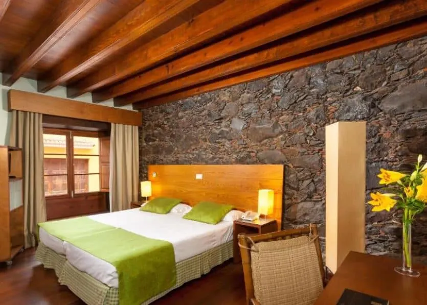 bedroom with stone walls, a desk with yellow flowers on it at the Hotel LIVVO La Quinta Roja in Garachico, Tenerife