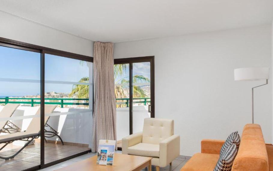 living room with sofa and balcony with sun lounges at Sunset Bay Club in Santa Cruz de Tenerife