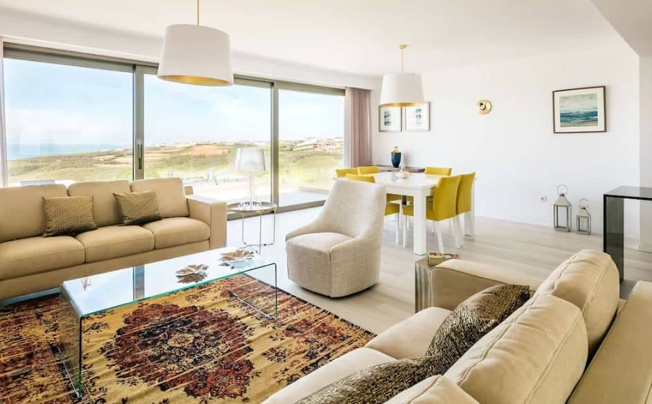 living room with sofa, dining table and big windows overlooking the sea at the Luxury Ocean View Villa with Private Pool in Atalaia, Portugal