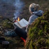 woman reading by the fire one of the best Non-Fiction Adventure Books