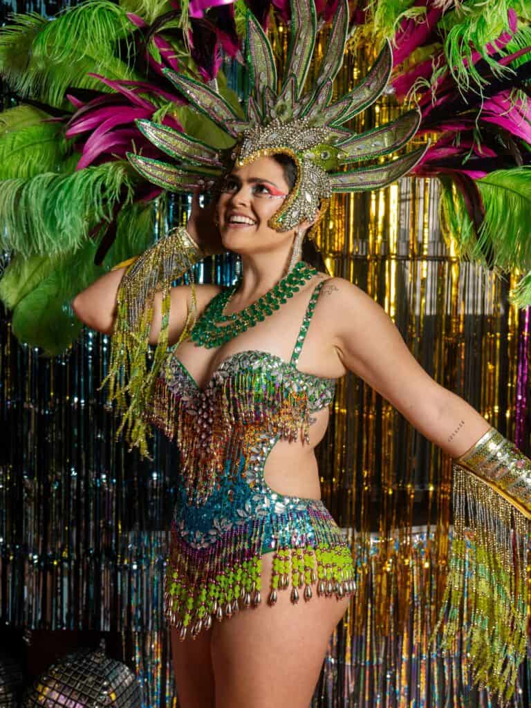 woman smiling wearing an extravagant pink and green carnival costume