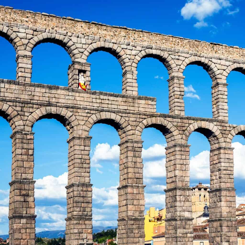 the aqueduct of segovia, spain with houses at the back on a bright day