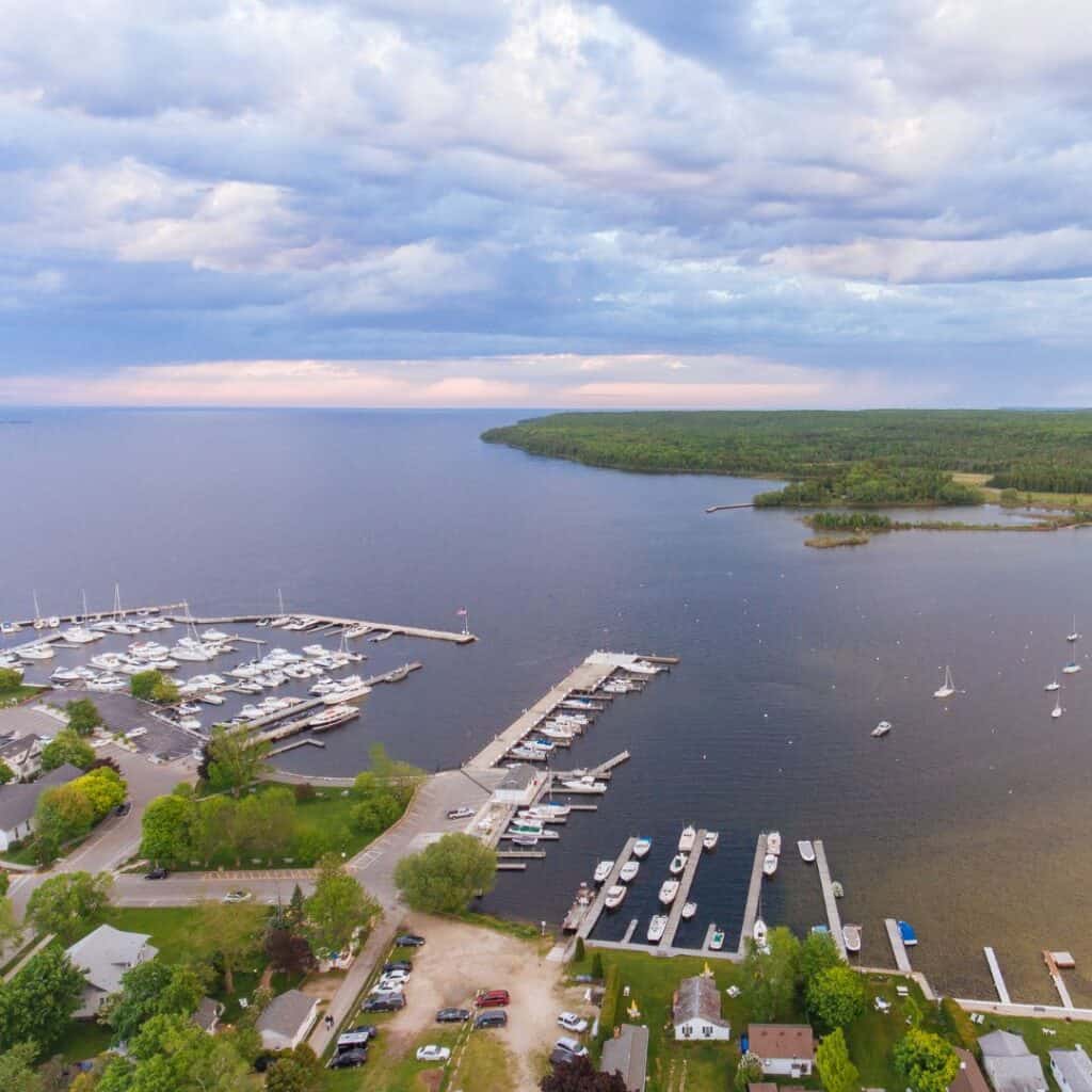 an aerial view of Fish Creekk harbor with boats docked, the seas and an island filled with green trees on a blue sky
