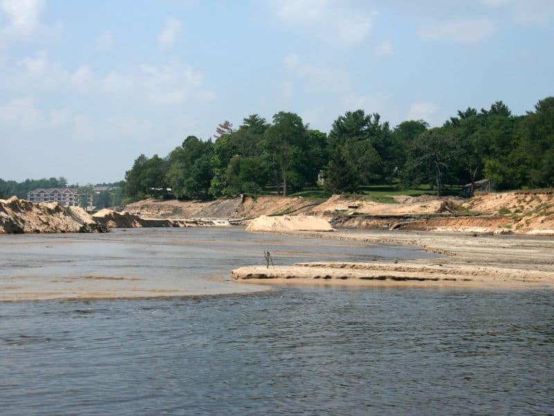 a body of water with sand and trees in the background