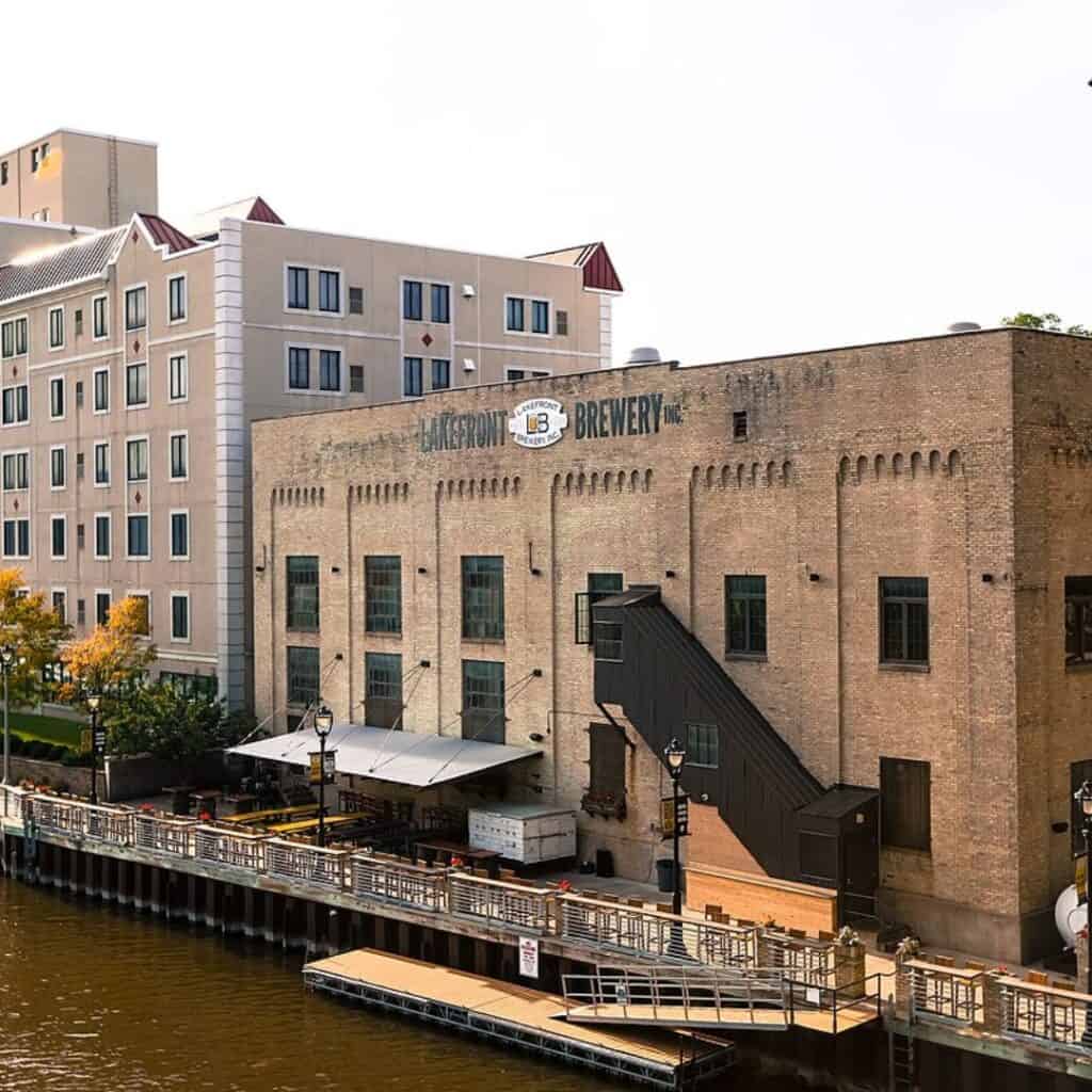 a view of a square building that is a brewery by a river 