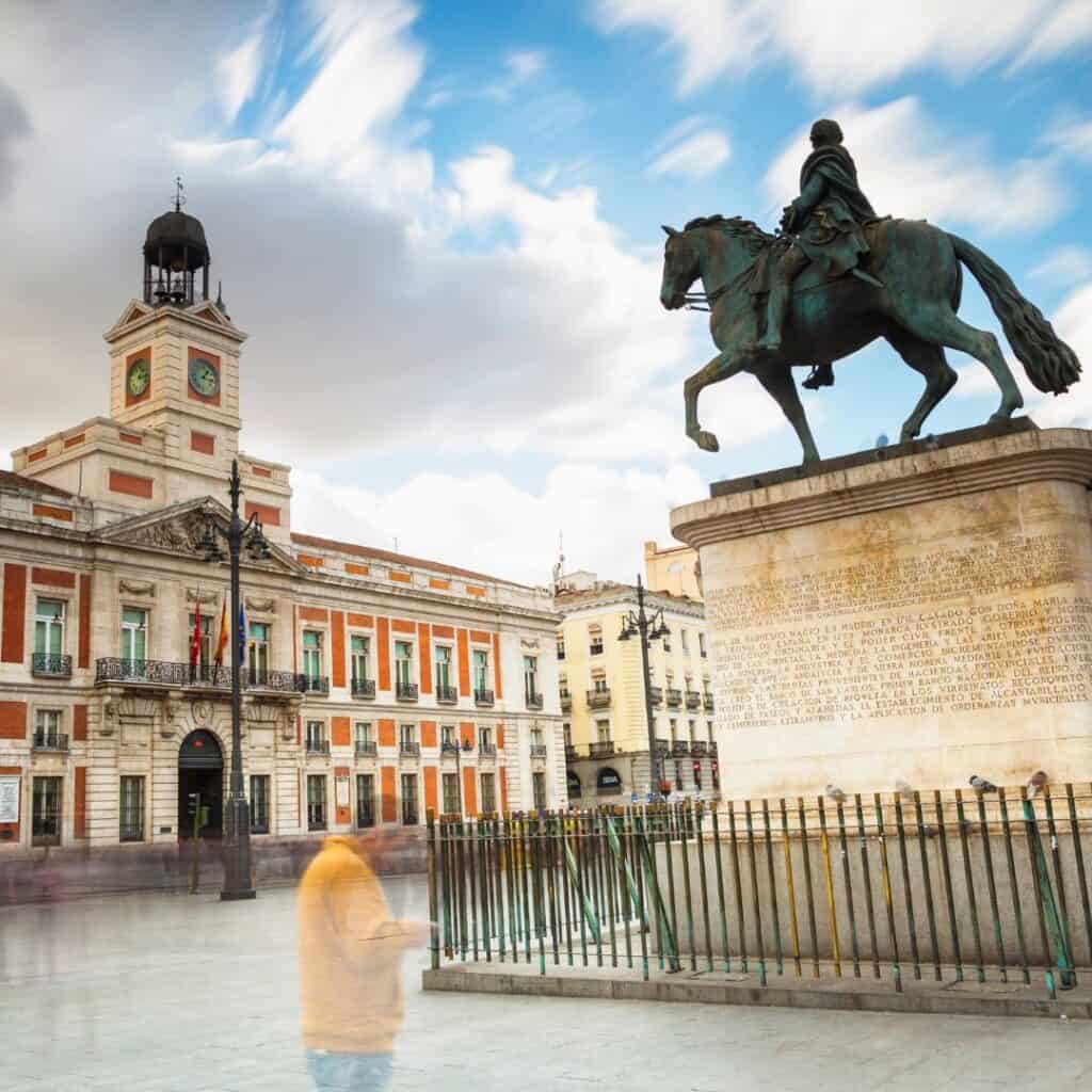 a statue of a person riding a horse in front of a red and white building