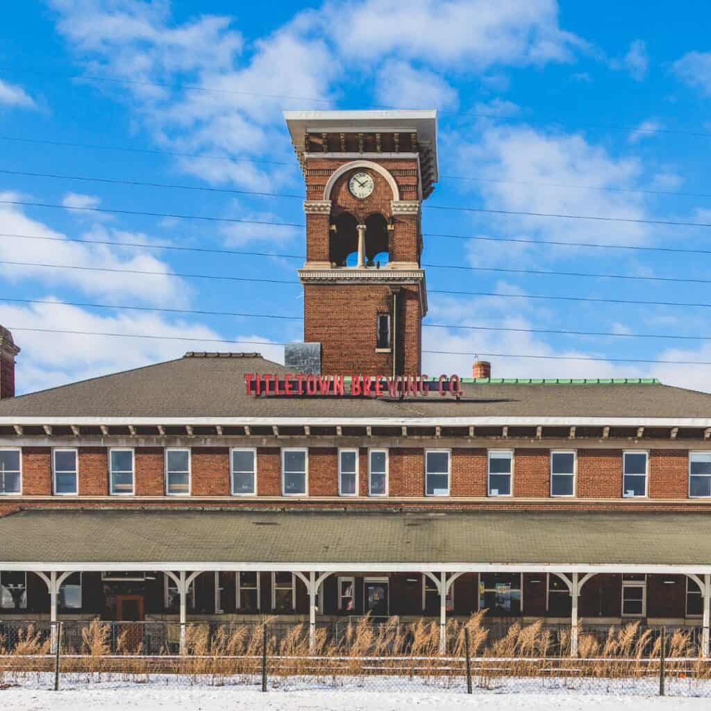 an old train station with a clock tower in the snow that is now a brewing company