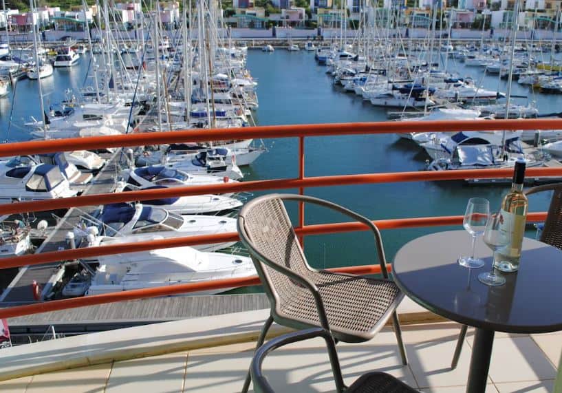 balcony with port view, a table with wine and glasses at Marina Apartment Old town in Albufeira