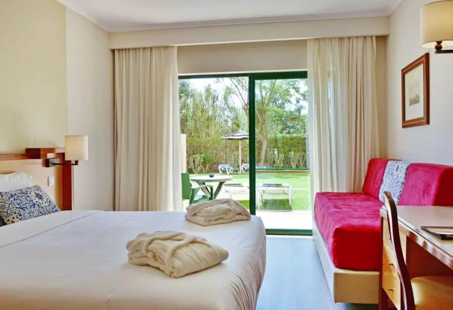 bedroom with sofa and balcony in the garden at the Real Bellavista Hotel & Spa in Albufeira