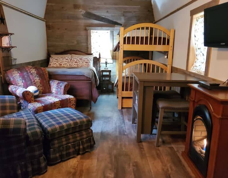interior of the Cozy Northwoods Mini Cabin with beds, arm chair, table and fire place in Blackwell, Wisconsin