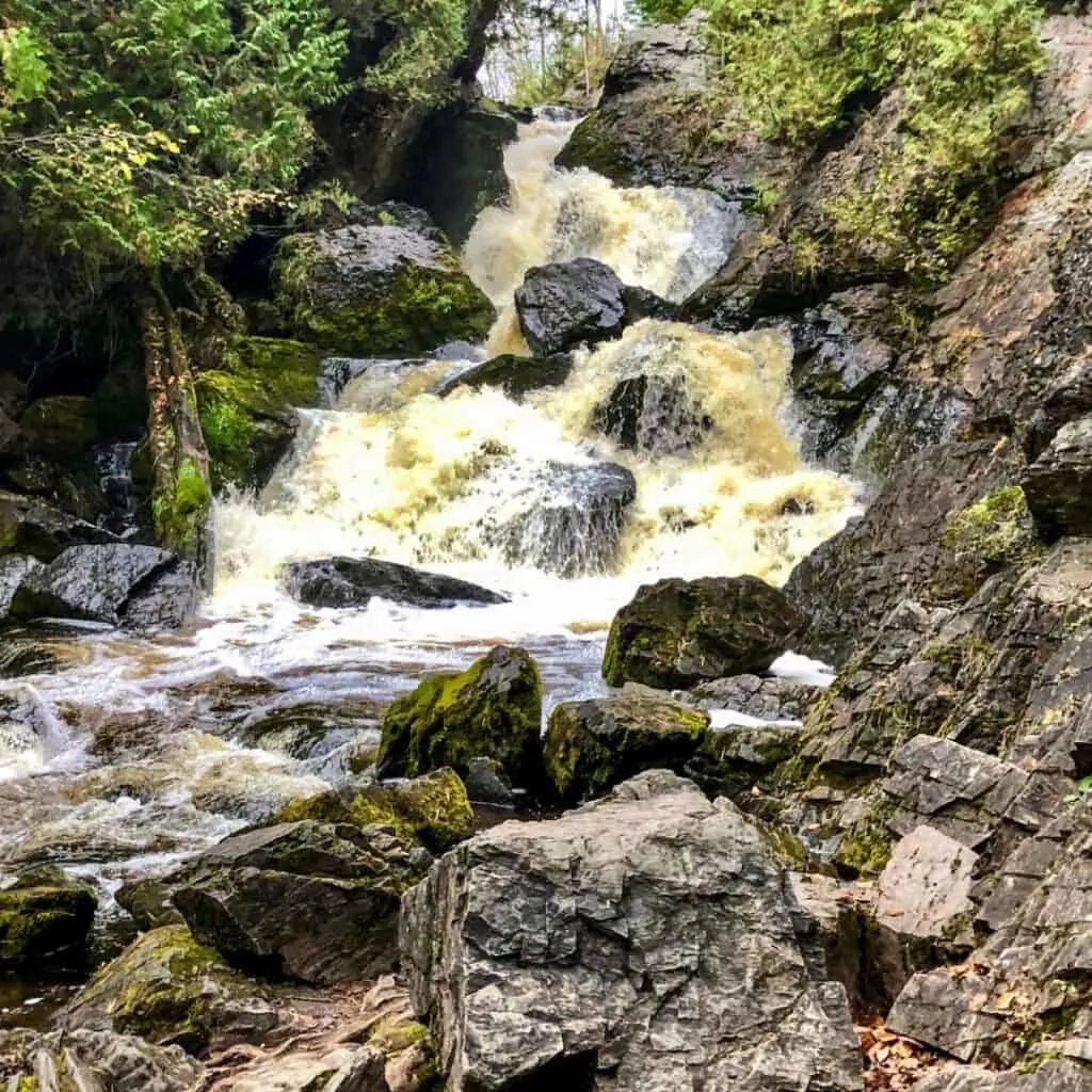 huge rock formations and gushing water flowing from long slide waterfalls in northeast wisconsin
