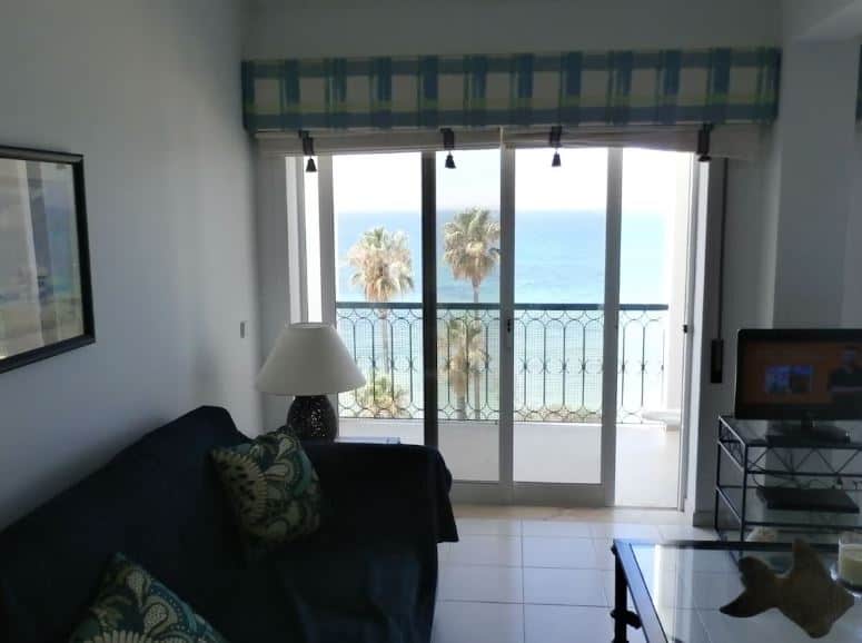 sofa and TV in a living room with balcony overlooking the sea at Condo facing the sea in Armação de Pêra