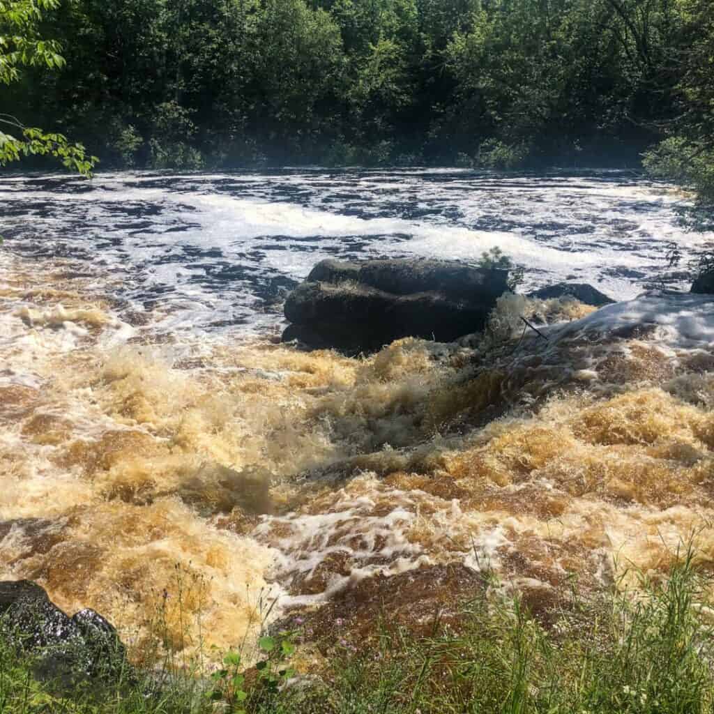 rapids and gushing water from strong falls in wisconsin with a large rock in the middle