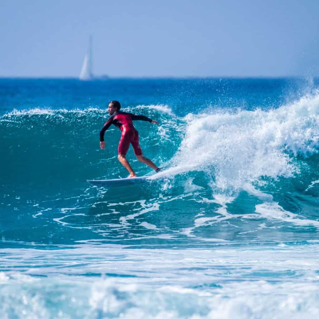 teenager wearing red wetsuit surfing big waves in tenerife