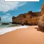 Pinterest pin about things to do in Albufeira in May, a smooth beach with no people, tall rocky cliffs, and small white waves