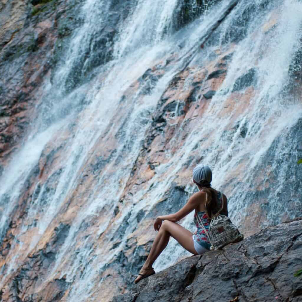 woman wearing cap sitting in large rock formation near waterfalls in northeast wisconsin