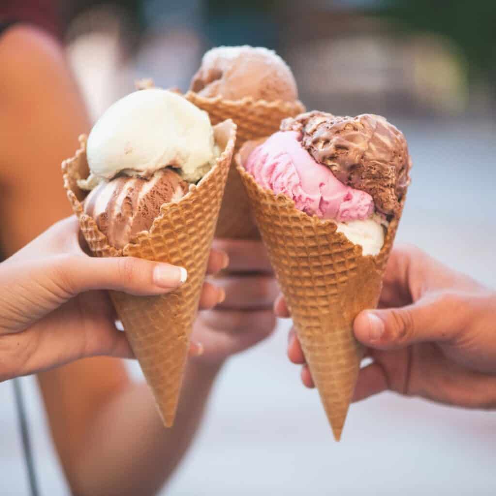 three people holding ice cream with different flavors on sugar cones