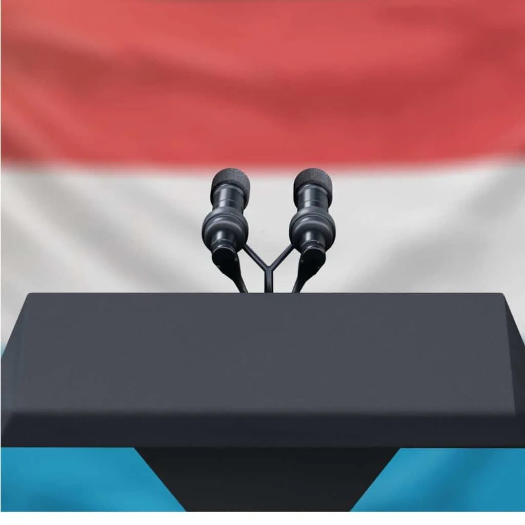 Podium lectern with two microphones and the flag of luxembourg in the background