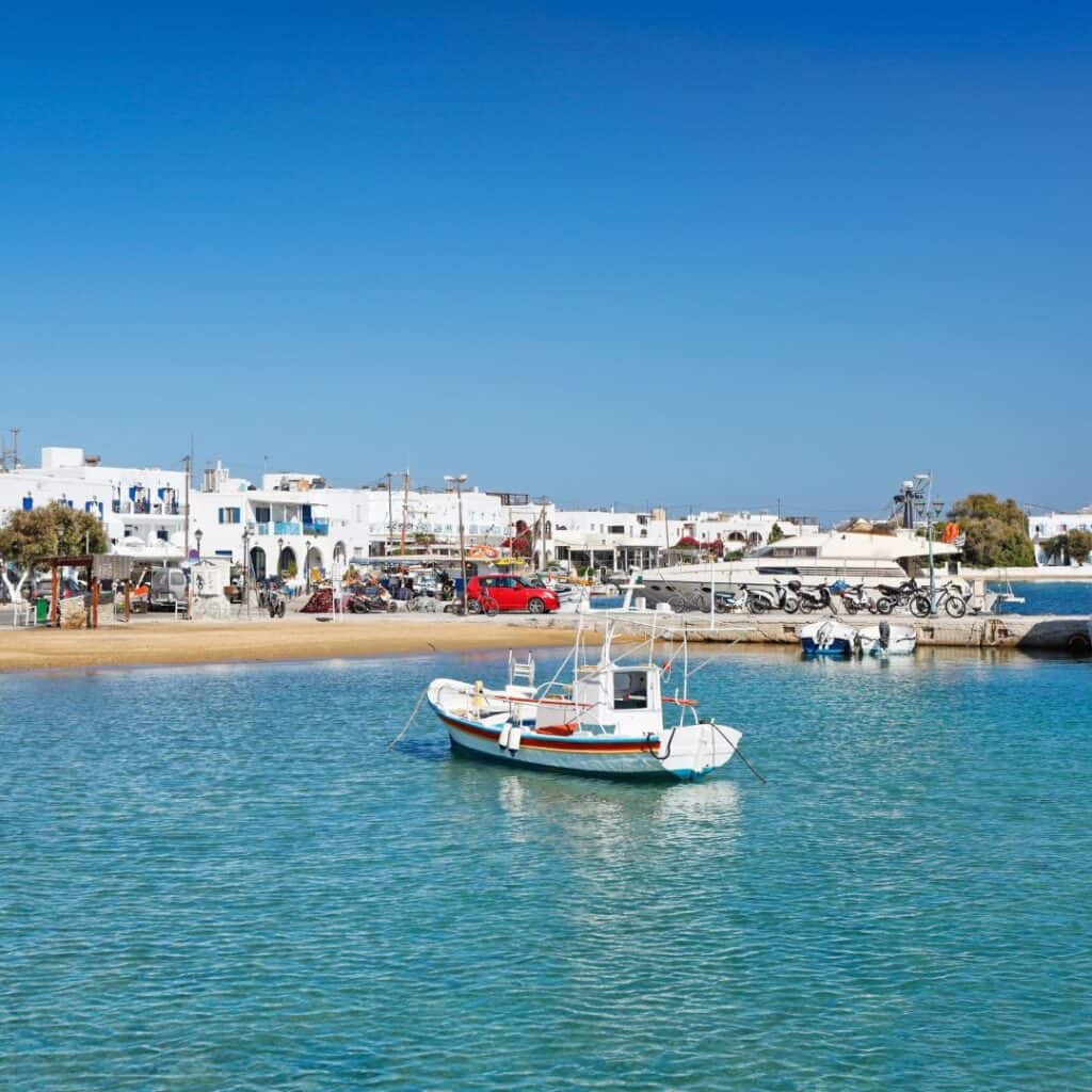 boats are docked in the clear blue water of a harbor with white houses by the beach port