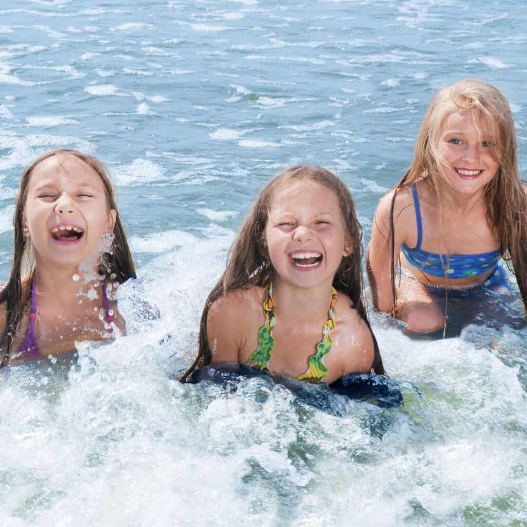 three girls smiling happily as they are swimming