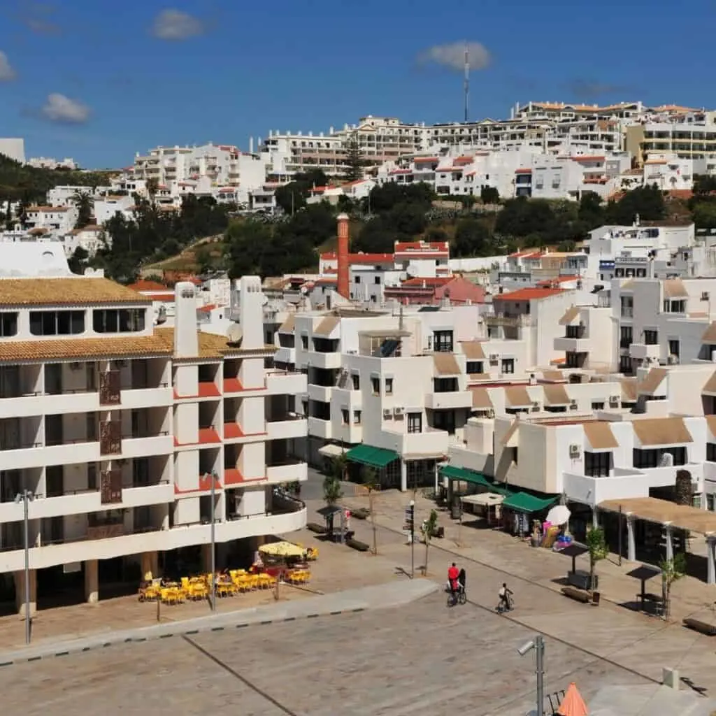 A photo of Albufiera Old Town, with a group of whitewashed buildings cluster on a hilltop overlooking the sea. Where To Stay In Albufeira for City Vibes.