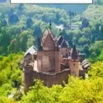 Pinterest pin about best castles in Luxembourg showing aerial photo of vianden castle with bright green foliage during a clear sunny day