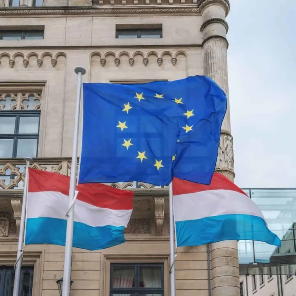 European union and Luxembourg flags waving in front of champer of deputies in luxembourg city
