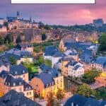 Pinterest pin about things to do in luxembourg by night, aerial shot of old town with lights amid a pink sky
