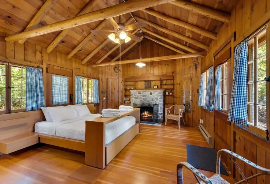 wooden bedroom with fire place and windows overlooking the forest at Lakefront Cottage in Jacksonport in Sturgeon Bay, Wisconsin