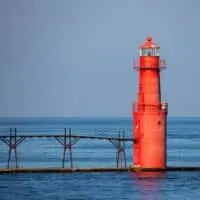a red lighthouse in the middle of a body of water that is one of the best lighthouses in Door County