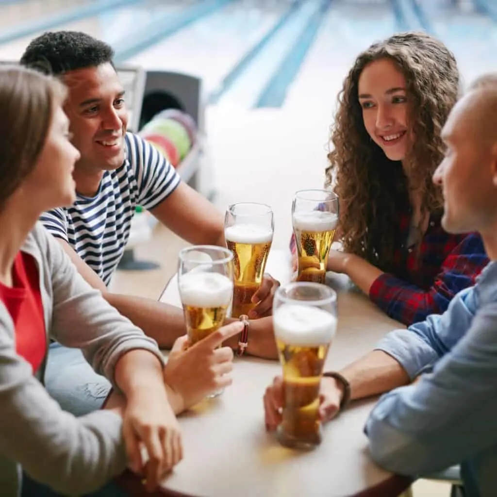 a group of friends having a beer at a bowling alley