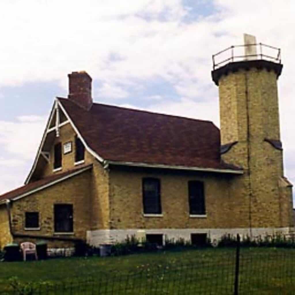 an old brick lighthouse with a water tower in the background