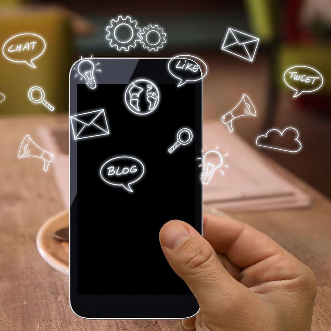 a hand holding an iphone with black screen with social icons popping out the screen