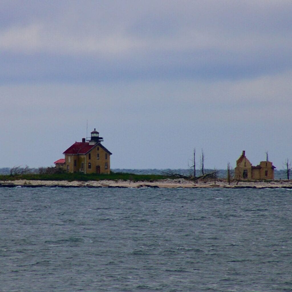 a lighthouse and a shack in a bare island in the sea