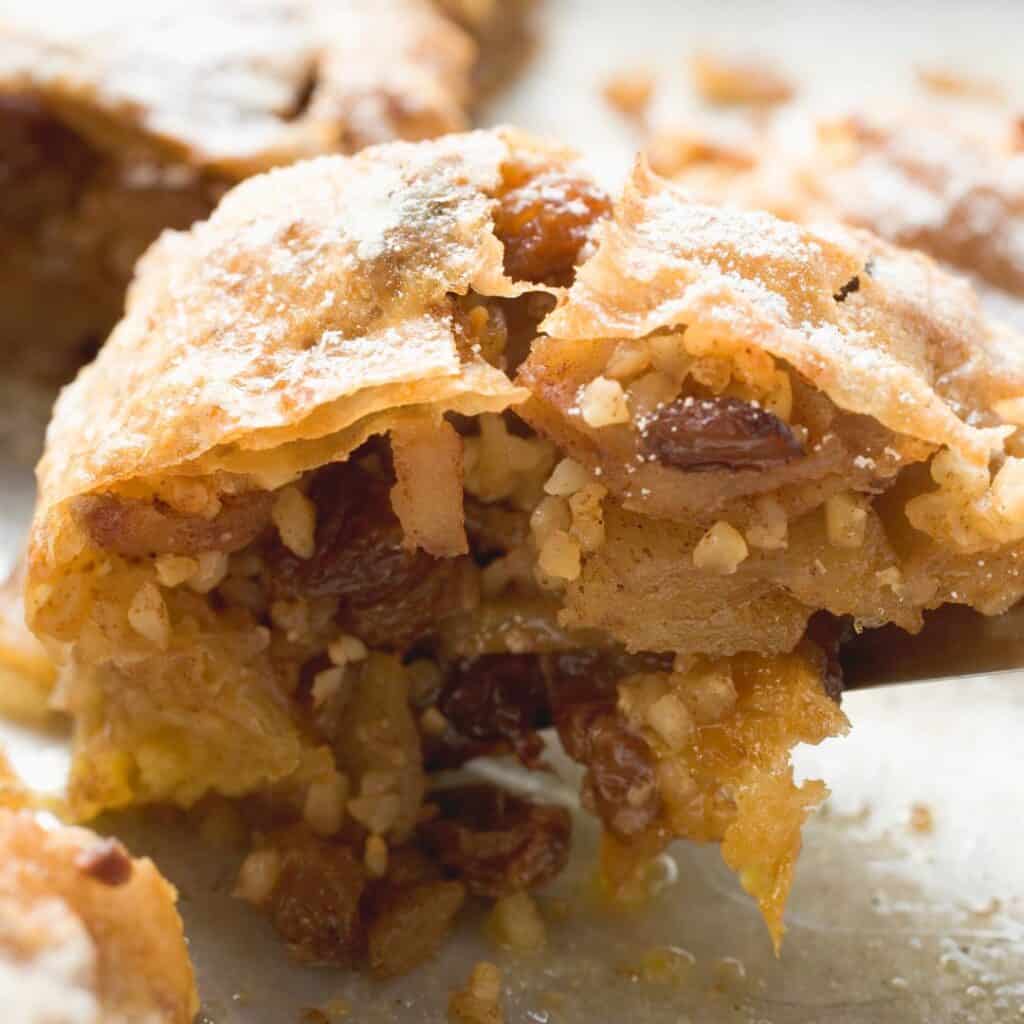 Closeup of slice of mummentaart with apple slices, raisins, and cinnamon with a flaky crust